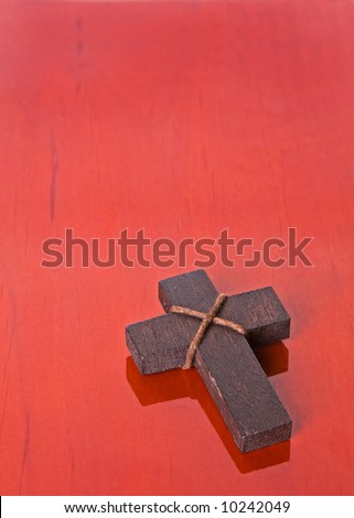 A wooden cross placed on a wooden table. Perfect for use with christian, religious, easter and christmas themes.