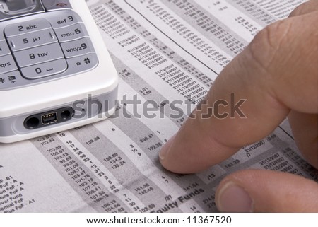 Finger pointing to share figures, with phone in the frame too. Shallow depth of field. Perfect for business concepts