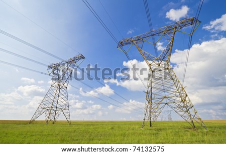 Super wide angle photograph of a row of power lines against a blue cloudy sky.