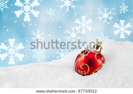 Red Christmas bauble lying in the snow. Christmas theme.