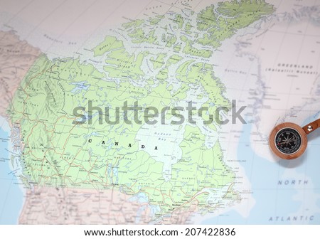 Compass on a map pointing at Canada and planning a travel destination