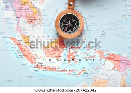 Compass on a map pointing at Indonesia and planning a travel destination
