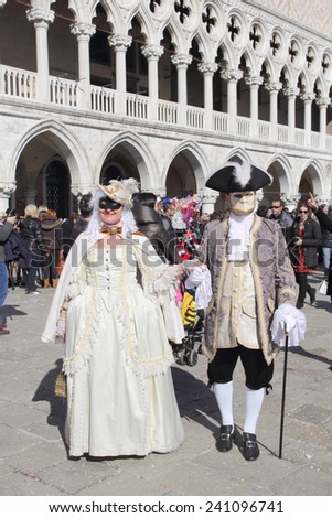 VENICE, ITALY - February 23: Unidentified masked couple walk in St. Mark\'s Square in Venice during the traditional festival of Carnival on February 23, 2014 in Venice, Italy