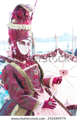 VENICE, ITALY - February 23: A red masked lady with parasol umbrella exhibited during the traditional festival of Carnival on February 23, 2014 in Venice, Italy