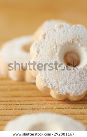 Italian butter biscuits piled on a wooden table. These cookies have a flower shape and covered with icing sugar