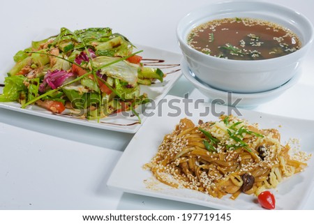 Japanese ramen noodles, soup and salad with sesame seeds on a white dish