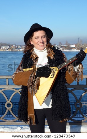 Lovely girl with balalaika is on embankment of Angara river in the city of Irkutsk