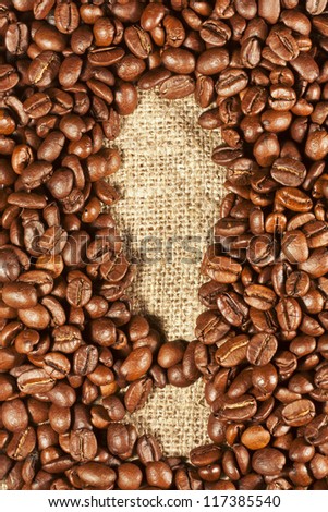Coffee beans in the shape of an exclamation mark on the background burlap