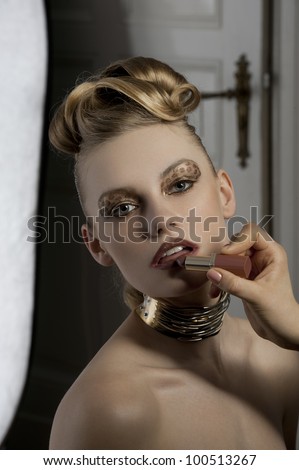 fashion portrait of cute and elegant woman getting makeup on backstage with spot light on her face