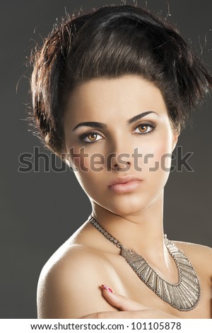 fashion beauty portrait of young pretty lady with hair style and an important old fashion silver necklace, she looks in to the lens, her arms are crossed and her hands are near the shoulders