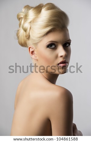 very pretty blonde woman with elegance hair style, she is turned at three quarters at right and looks in to the lens with serious expression