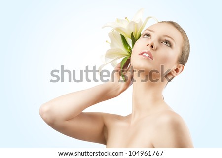 beauty portait of pretty young girl with lilies, she looks up and takes lilies near the right ear