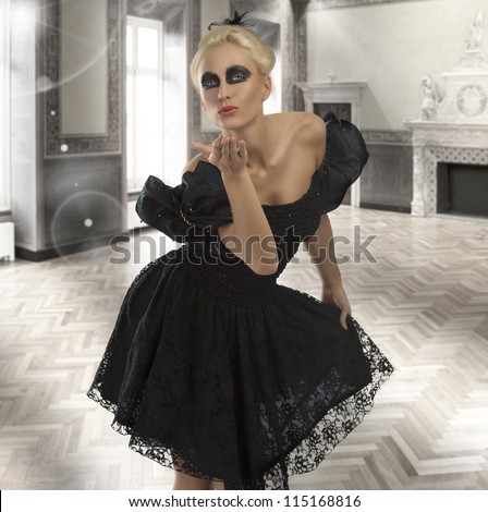pretty blonde girl with gothic dress and dark make-up, she sends one kiss with right hand and touches the dress with left hand