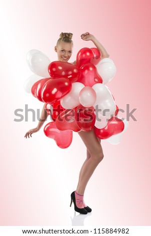pretty girl with red and white balloons on her body, turned on thrree quarters at left looks in to the lens with open arms