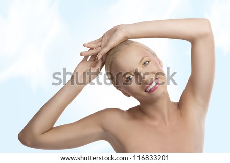 pretty blonde girl with naked shoulders and colored make-up, she looks in to the lens and laughs with both hands on the head