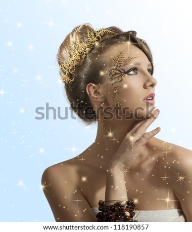 beautiful woman with christmas make-up and hair decoration, she looks at left with hand under the chin