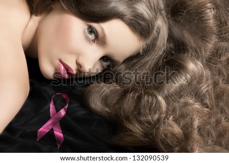 pretty young girl in a close up portrait laying down near a pink bow with curly hair