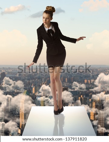 pretty blonde business woman with formal suit and heels keeping her balance on trampoline