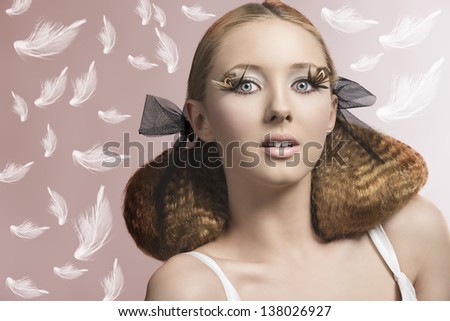 close-up portrait of fashion blonde girl with feathered make-up, creative hair-style and white dress on pink background