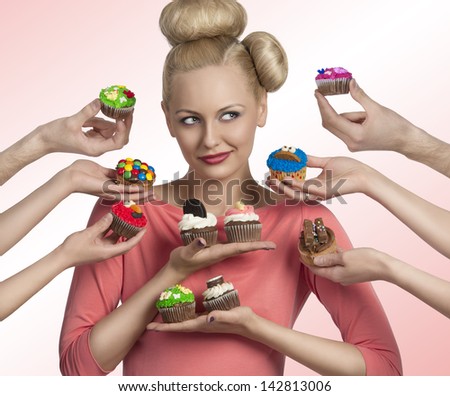 portrait of blonde woman with funny make-up and hair-style. Some hands tendering colorful cupcakes near her face