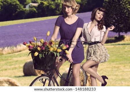fashion portrait of couple sensual girls with vintage style near bicycle with floral basket