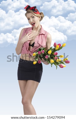 portrait of happy pin-up woman with sexy style, blonde hair-style wearing short skirt and open shirt taking colourful flowers in the hand