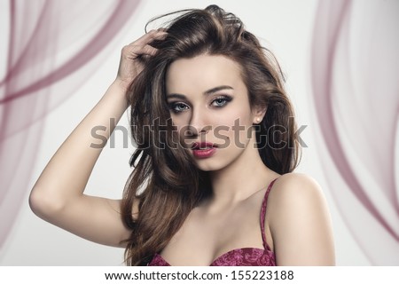 glamour portrait of brunette girl with long smooth hair, cute make-up and sensual eyes. Wearing red lingerie