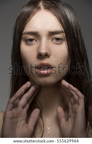 close-up portrait of beauty clean girl with natural style, wet visage skin and hair. Looking in camera with hands near the face