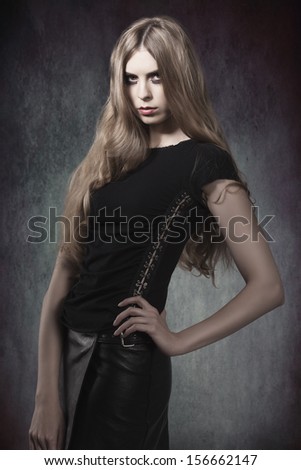 fashion portrait of gothic girl with Halloween make-up and dark dress in sensual pose with long blonde hair