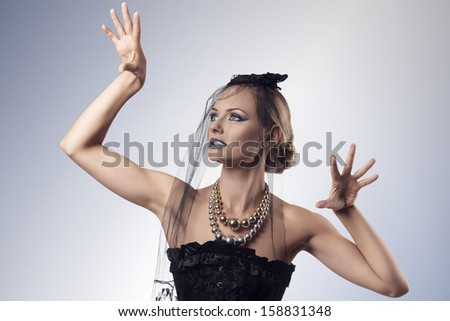 portrait of attractive blonde girl with goth style in the halloween day in aggressive pose. She wearing dark veil on the face, black corset and creative make-up