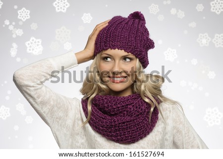 between fake snow young and sexy blond girl wearing purple scarf and hat in winter dress over white