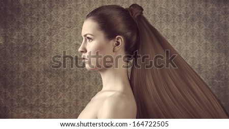 pretty young girl with naked shoulder and long hair tail in a grunge background