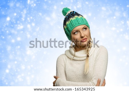 cold girl in winter dress , with green hat arming herself in act to warm and looking away with eyes