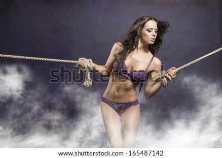 hot portrait of very sexy brunette girl with long flying hair tied by rope. She wearing purple underwear