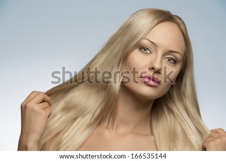 close-up portrait of sensual blonde woman with natural look and perfect skin showing her long smooth silky hair