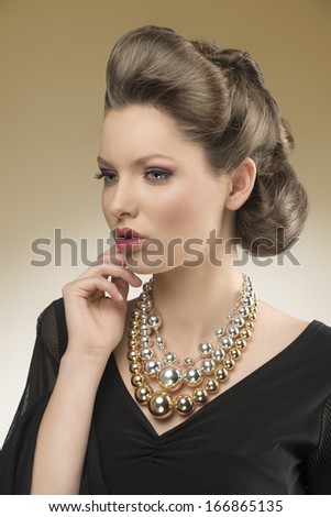 close-up portrait of sensual woman with aristocratic style posing with elegant hair-style and black dress, wearing big bright necklace
