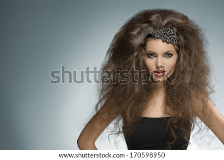 sexy brunette girl with long curly voluminous hair-style and glitter accessory in the hair posing in fashion portrait with cute make-up