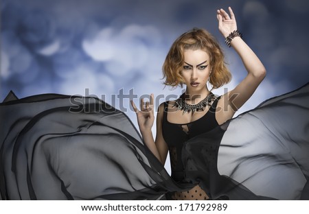 very sexy girl with bizarre gothic make-up, style and accessories posing in fashion portrait with long veil flying skirt. Carnival look