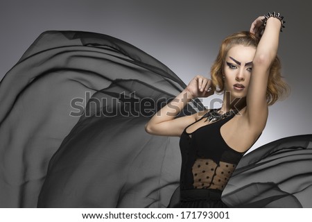 creative portrait of fashion bizarre woman with strong gothic make-up and rock accessories. Posing with big veil flying skirt. Carnival look