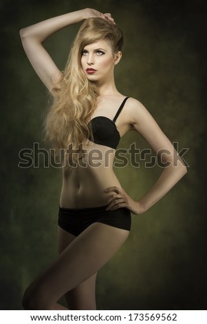 very sexy blonde woman with black lingerie and long wavy blonde hair showing her perfect body in sensual pose