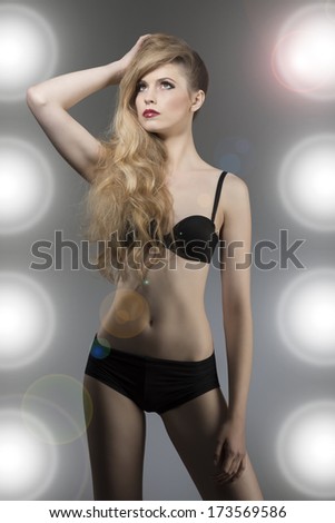 fashion portrait of sexy blonde girl with black lingerie and long wavy blonde hair posing with her perfect body