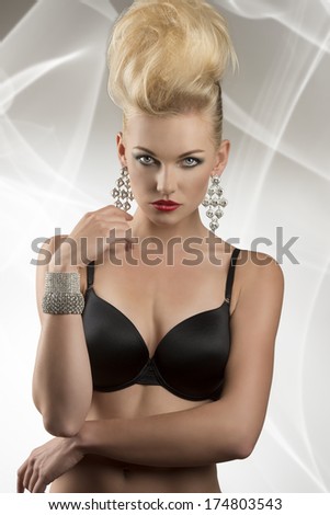 seductive female posing in glamour portrait with lingerie and creative hair-style. Wearing black bra and glossy jewelleries
