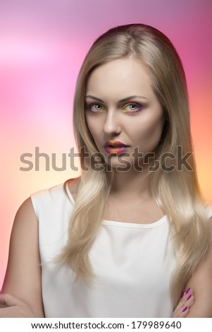 sexy blonde girl posing with creative colorful make-up, long silky smooth hair and white dress