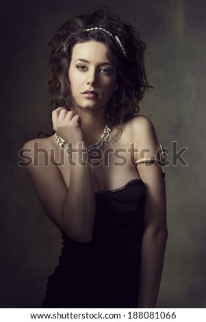 fashion portrait of very sensual brunette woman with curly hair-style, wearing creative jewels and sexy dress