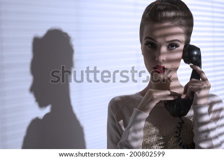 sexy female with elegant hair-style and make-up talking on the phone with vintage receiver