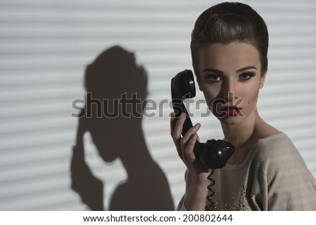 charming woman with vintage style and elegant hair-style talking on the retro phone, taking receiver near the face