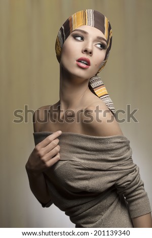 fashion woman with foulard on the head in sensual pose with naked shoulders and brown dress