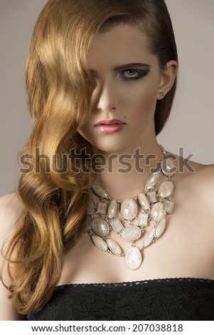 close-up of very pretty female with elegant wavy hair-style, sexy black dress and stylish necklace.