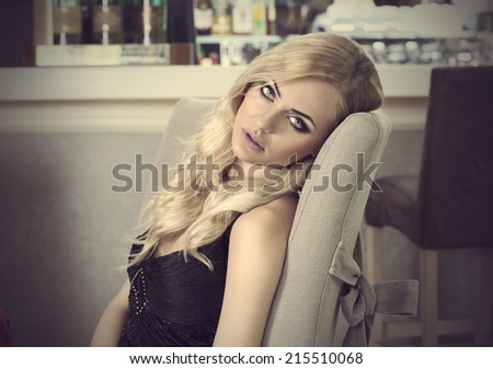 romantic portrait of blond girl sitting at restaurant . waiting somebody . she is very elegant and looking in camera