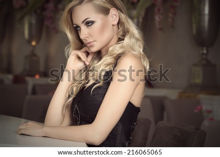 thinking elegant girl in black , with curly hair sitting at the restaurant bar waiting . old fashion style